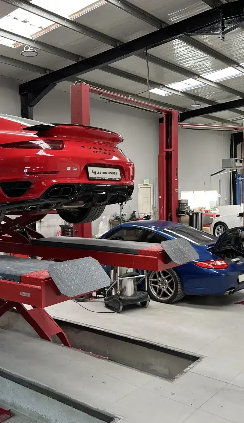 Red Porsche raised on a workshop lift